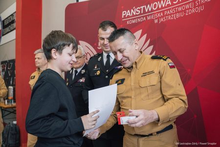 Przedstawiciel Straży Pożarnej wręcza nagrodę chłopcu z drugiej grupy