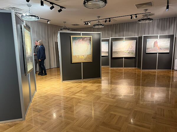 Sala z obrazami wiszącymi na czarnych ściankach