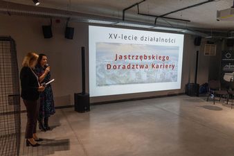 Prezenterki obok ekran z prezentacja XV lecie działalności Jastrzębskiego Doradztwa Kariery