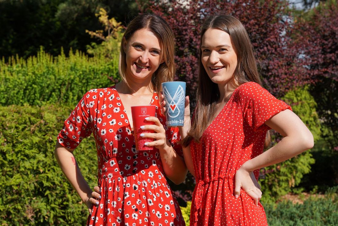 Dwie uśmiechnięte dziewczyny z miejskim kubeczkiem