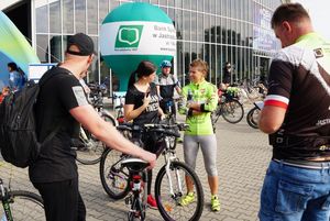 Grupa rowerzystów przed halą widowiskowo-sportową