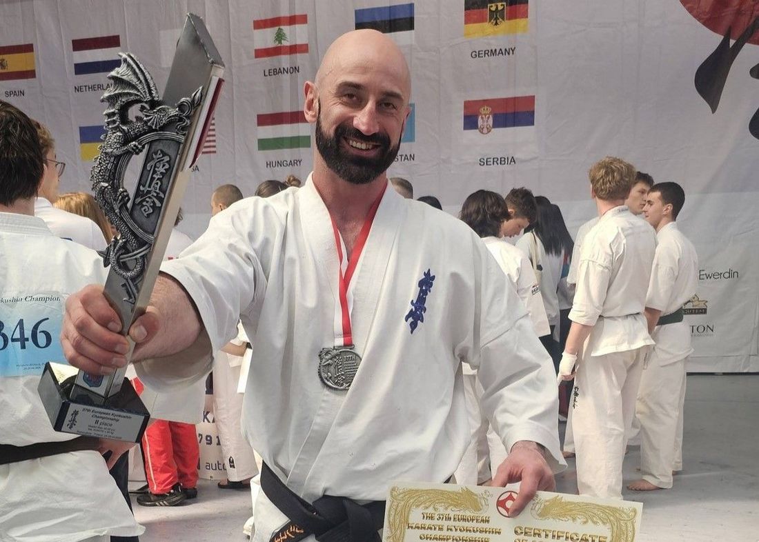 Łukasz Janczukowicz cieszący się z medalem, pucharem oraz dyplomem