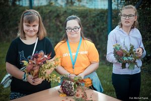 Uczestnicy warsztatów wykonują ozdoby z suchych roślin.