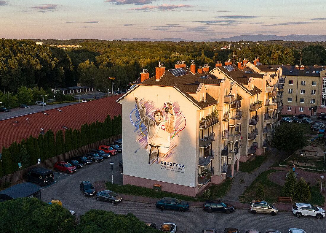 Na bocznej elewacji bloku znajduje się duży mural przedstawiający judoczkę w białym kimonie z godłem Polski, unoszącą ręce w geście zwycięstwa i trzymającą medal. W tle postaci znajdują się kółka olimpijskie oraz napis „KRUSZYNA” wraz z podpisem (Beata Maksymow-Wendler)