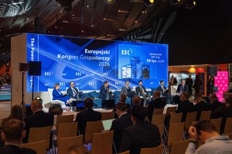 Uczestnicy siedzą i słuchają panelistów, którzy ze sceny mówią