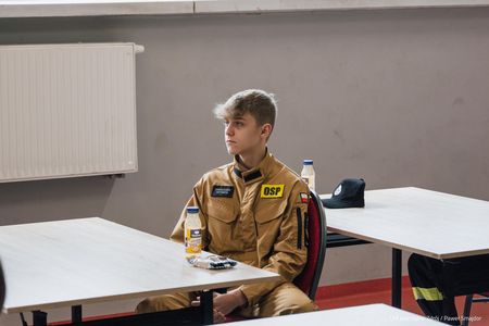 Nastolatek w stroju strażackim siedzący przy stoliku