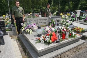 Grób powstańca udekorowany kwiatami i plakietką