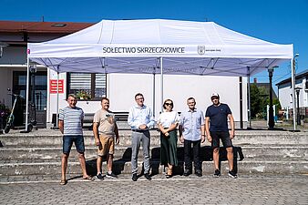 6 osób stojących przed namiotem.