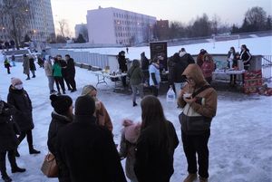 Grupa wolontariuszy przed sztabem WOŚP. W tle stoisko z kiełbaskami