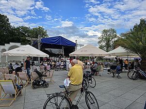 Scena z oddali, na pierwszym planie osoby z rowerami słuchające występu