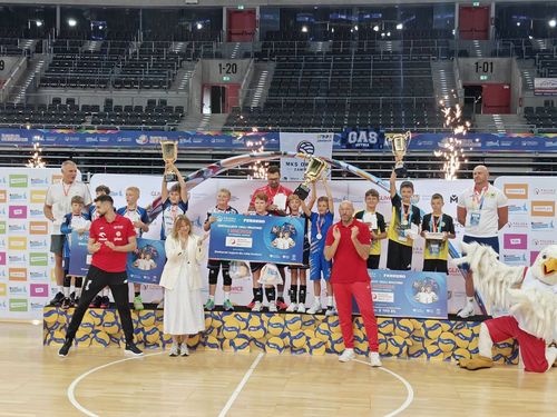 Ceremonia dekoracji dzieci na podium w hali sportowej z maskotką orła