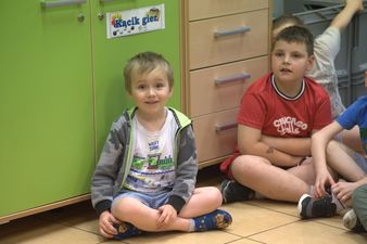 usmiechnięty chłopiec siedzi po turecku 