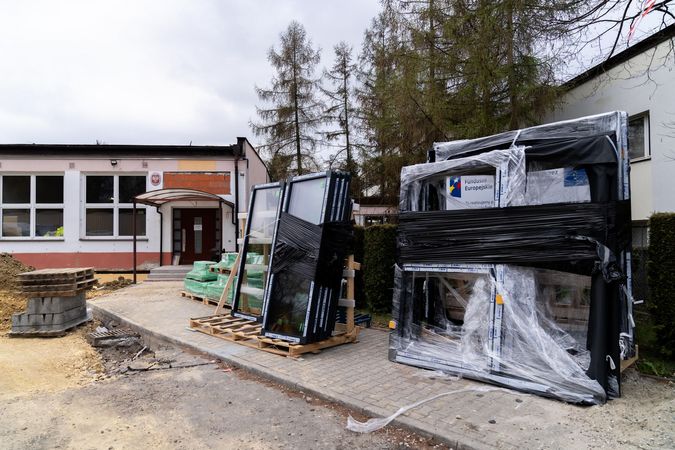 Budynek CKZ przed nim na paletach zafoliowana stolarka okienna