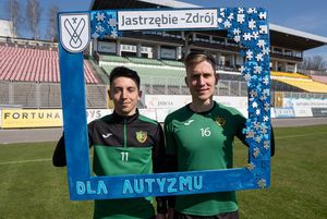 Piłkarz GKS Jastrzębie trzymają drewnianą, niebieską ramkę z napisem "dla autyzmu"