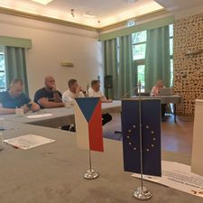 uczestnicy siedza przy stole i słuchają prowadzącej