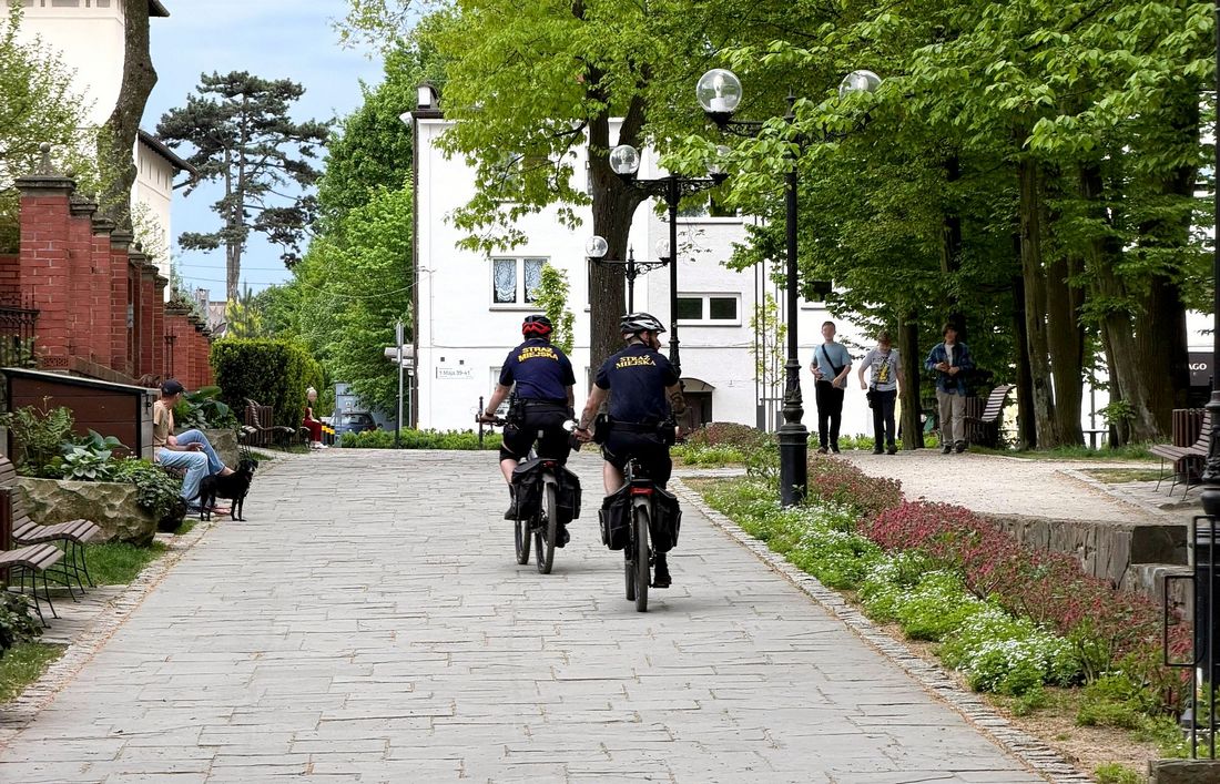 dwóch strażników miejskich jedzie na rowerach w parku zdrojowym