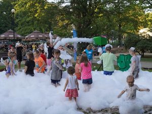 Dzieci bawią się w pianie, śmiejąc się i biegając