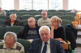 Bliskie ujęcie na uczestników spotkania siedzących w rzędach zielonych foteli