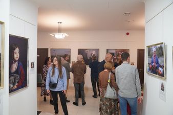 Ludzie na wernisażu oglądający obrazy i fotografie wiszące na jasnych ścianach