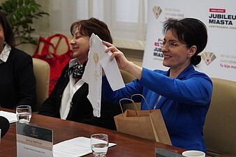 Prezydent Anna Hetman prezentuje body wchodzace w skład wyprawki jubileuszowej dla noworodka