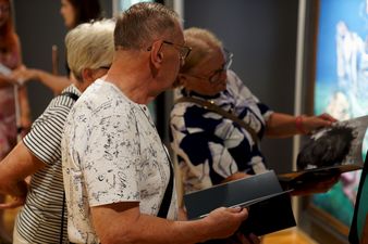 Dwie kobiety i jeden mężczyzna przeglądają folder poświęcony wystawie
