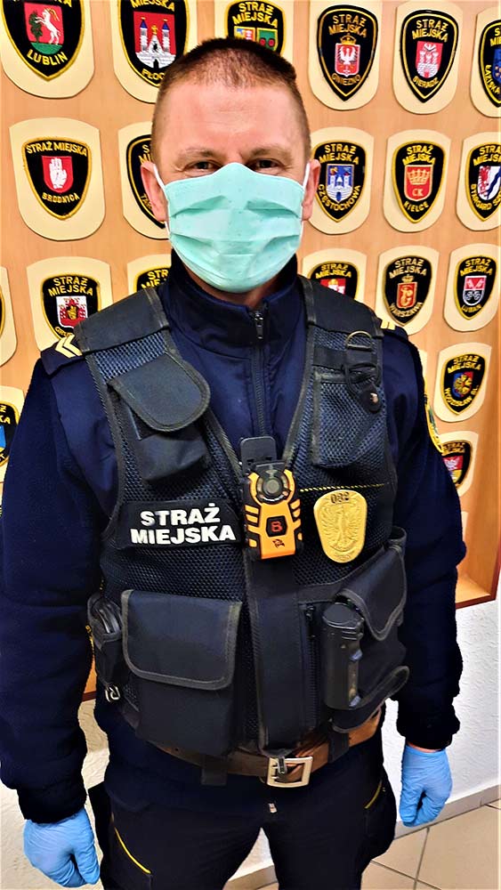 Zdjęcie przedstawia strażnika z zamontowaną kamerą na klatce piersiowej.
