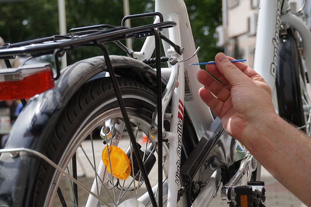 Zdjęcie - strażnik nanosi syntetyczne oznakowanie na rower.