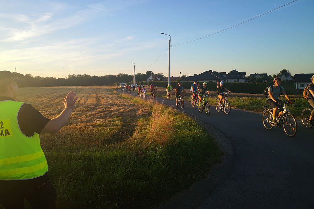 Uczestnicy rajdu machają do strażnika miejskiego, który zabezpiecza trasę.