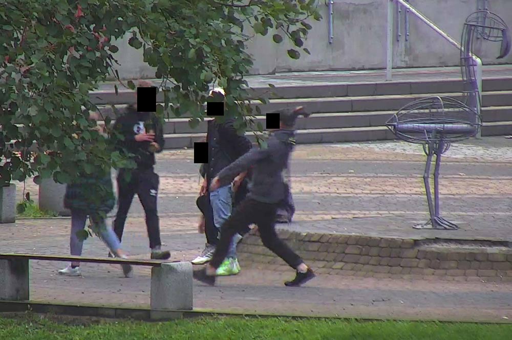 Kadr z monitoringu miejskiego - wandale rzucają kostką brukową.