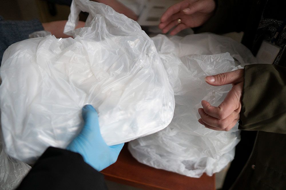 Zdjęcie przedstawia zapakowany posiłek przekazywany w ręce osoby.