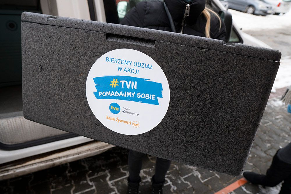 Zdjęcie przedstawia pojemnik na posiłki z logo akcji trzymany przez dostawcę.