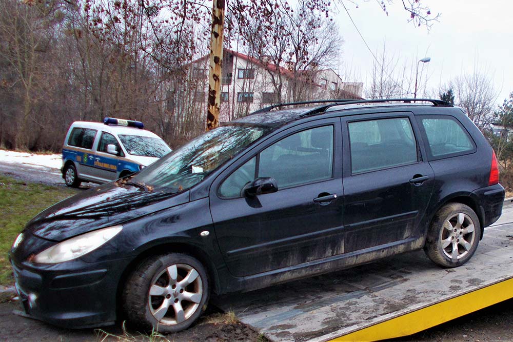 Przedstawia Peugeota wciąganego na lawetę.