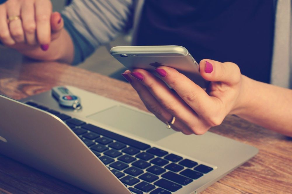 Zdjęcie ilustracyjne: kobieta korzystająca z laptopa i smartfona