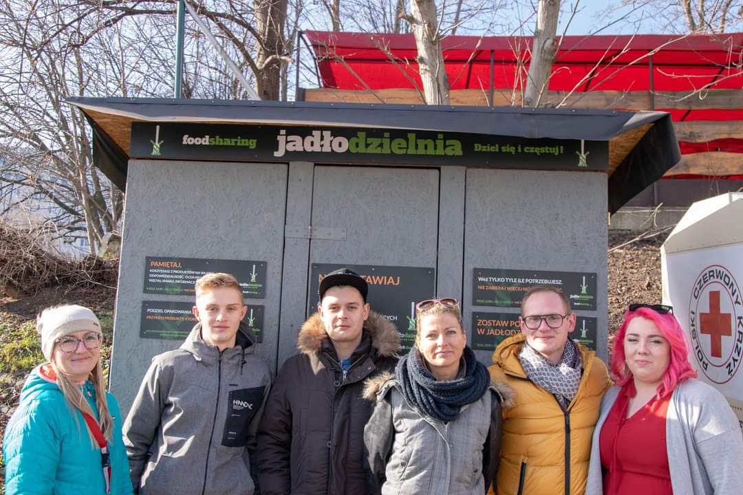 sześć osób stoi pod jadłodzielnią