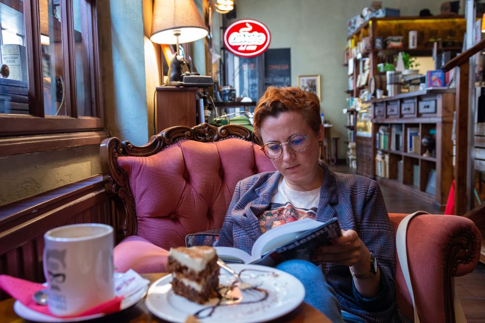 Agnieszka Witczak, siedząca w fotelu w kawiarni i czytająca książkę