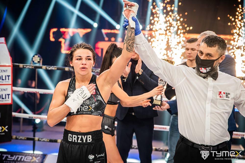 Przedstawia Laurę na ringu po walce - sędzia unosi w górę jej rękę.