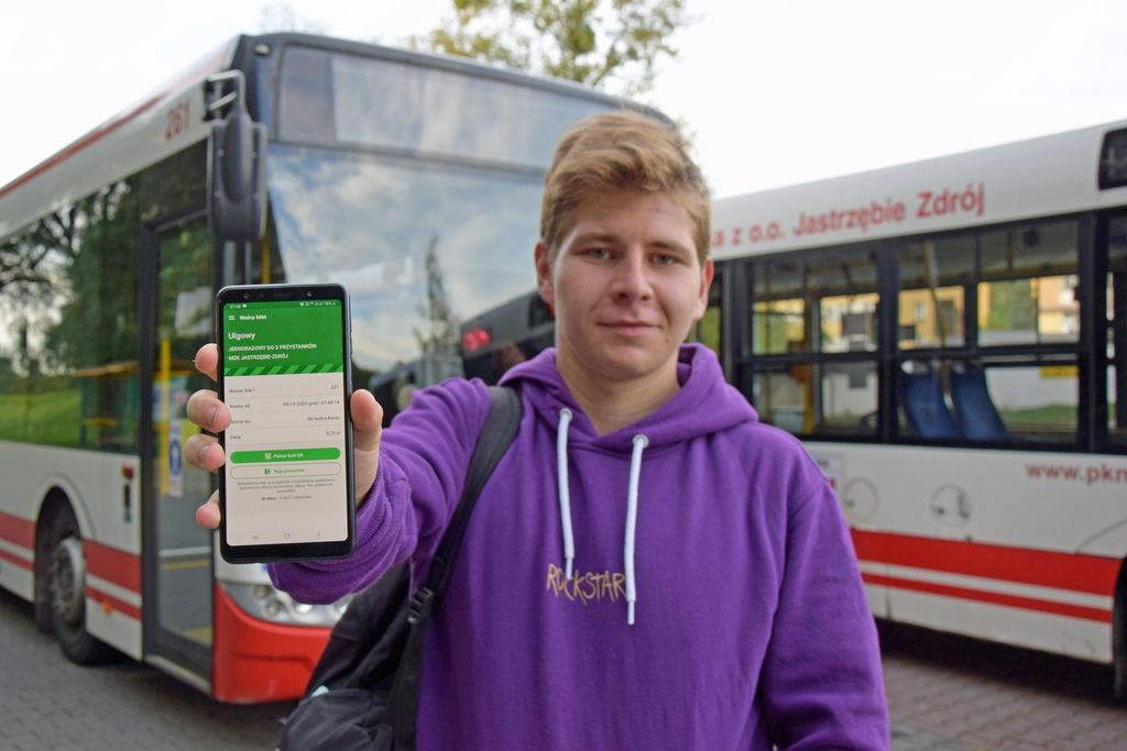 Uśmiechnięty chłopiec trzyma telefon komórkowy z biletem elektronicznym