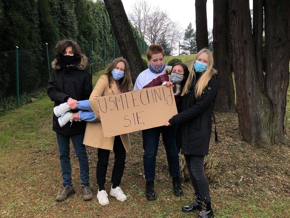 grupa licealistów z projektu Słowa Mają Moc trzyma karton z napisem "Uśmiechnij się"