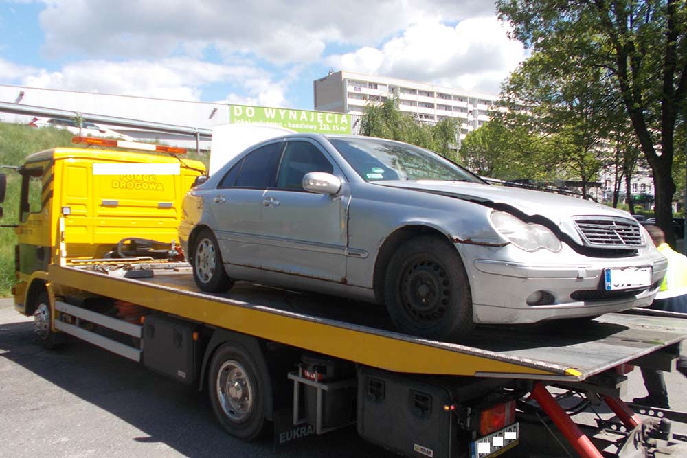 Widać na nim srebrny samochód zaparkowany na lawecie.