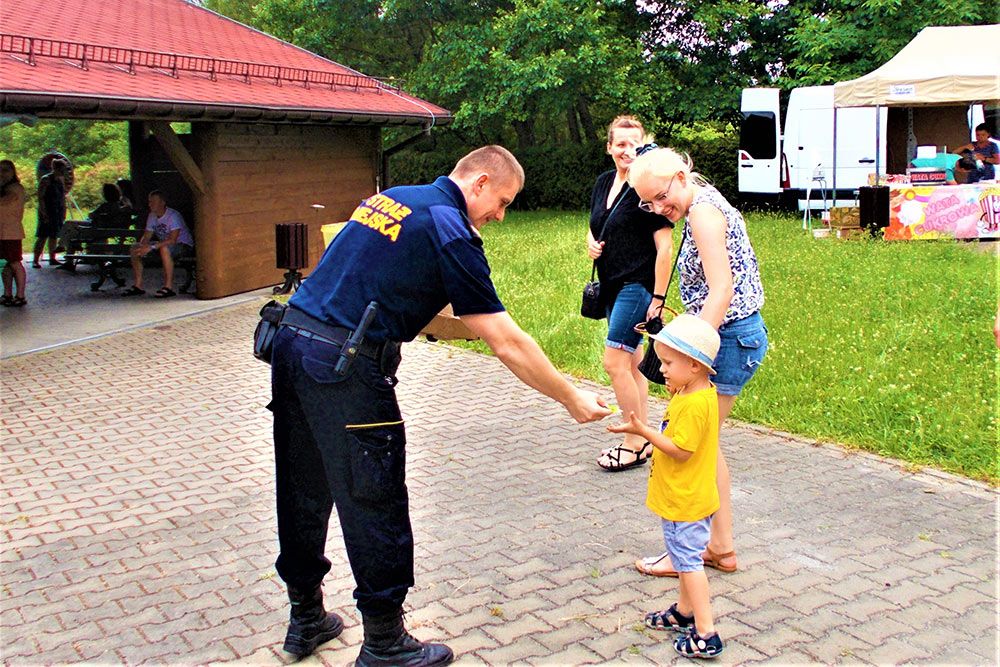 Strażnik wręcza dziecku element odblaskowy.