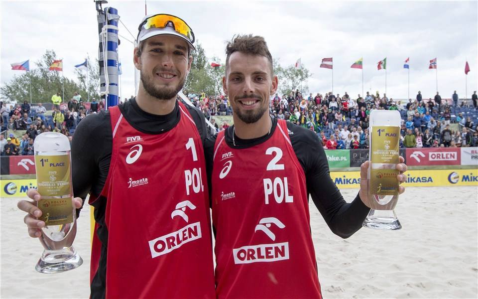 Zdjęcie przedstawia Bartosza Łosiaka i Piotra Kantora, którzy pozują do zdjęcia z trofeami za turniej FIVB World Tour w Warszawie.