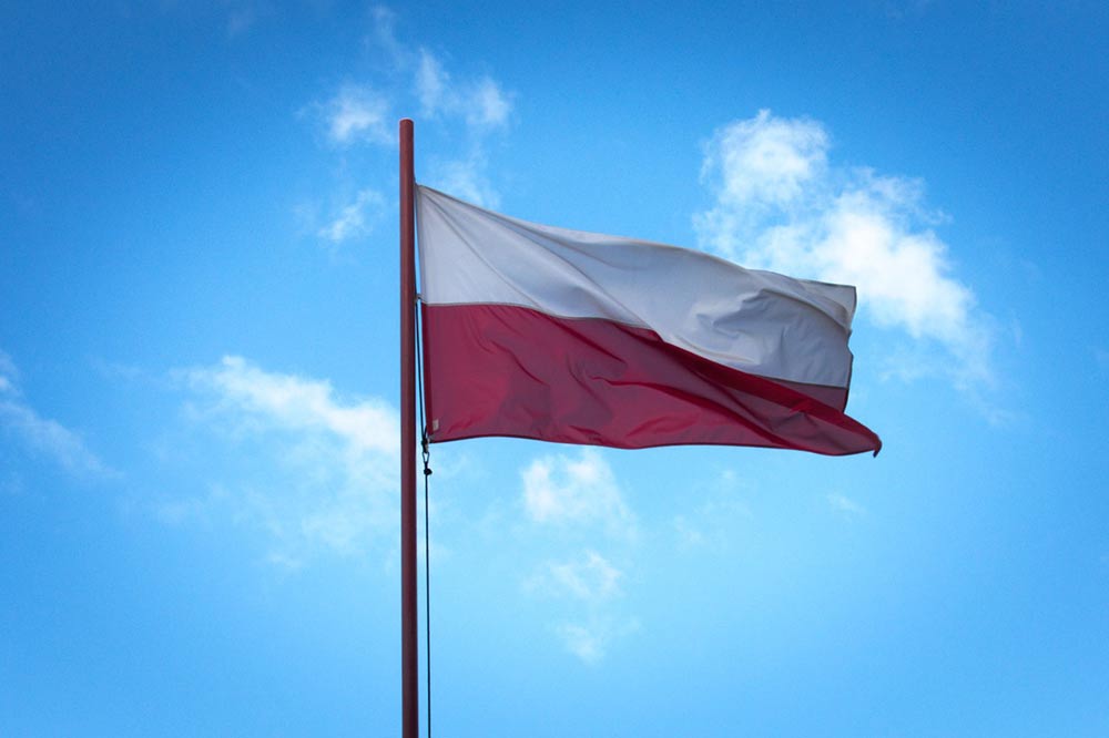 Zdjęcie przedstawia flagę Polski na maszcie.