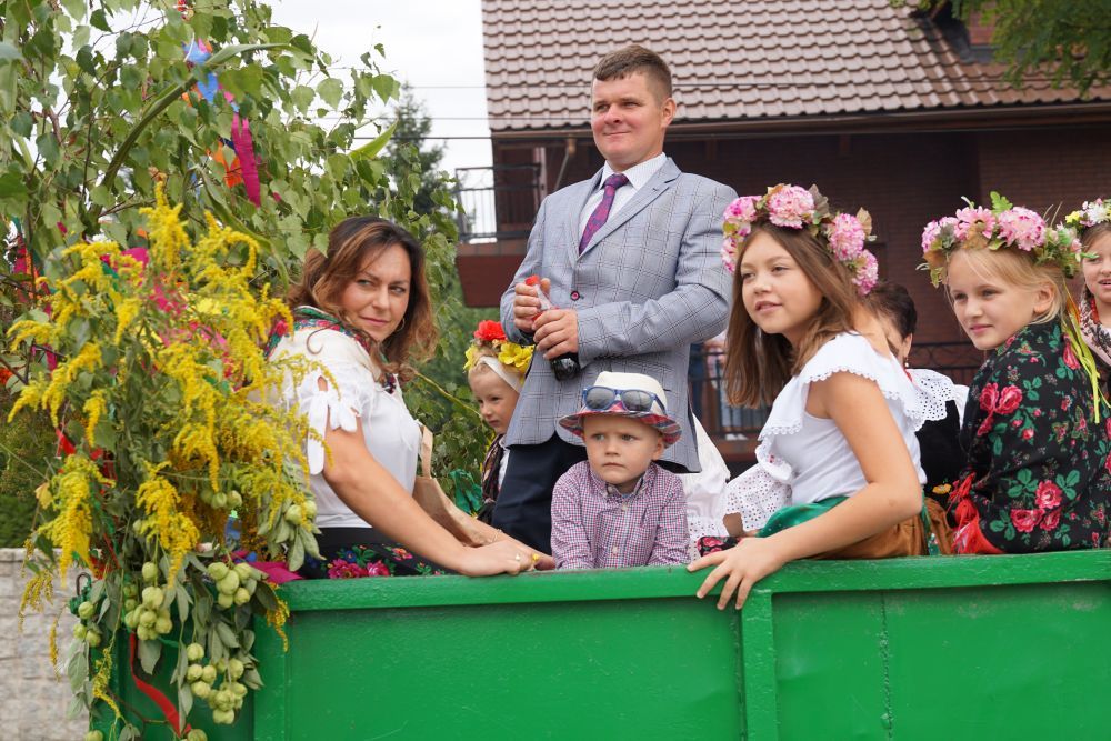na wozie siedzą osoby w strojach ludowych