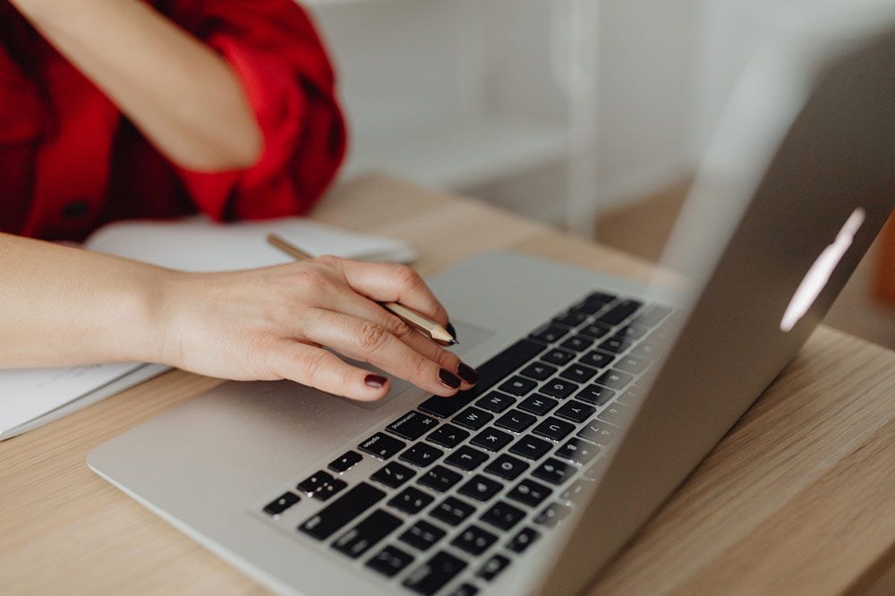 Zdjęcie - dłoń na klawiaturze laptopa.