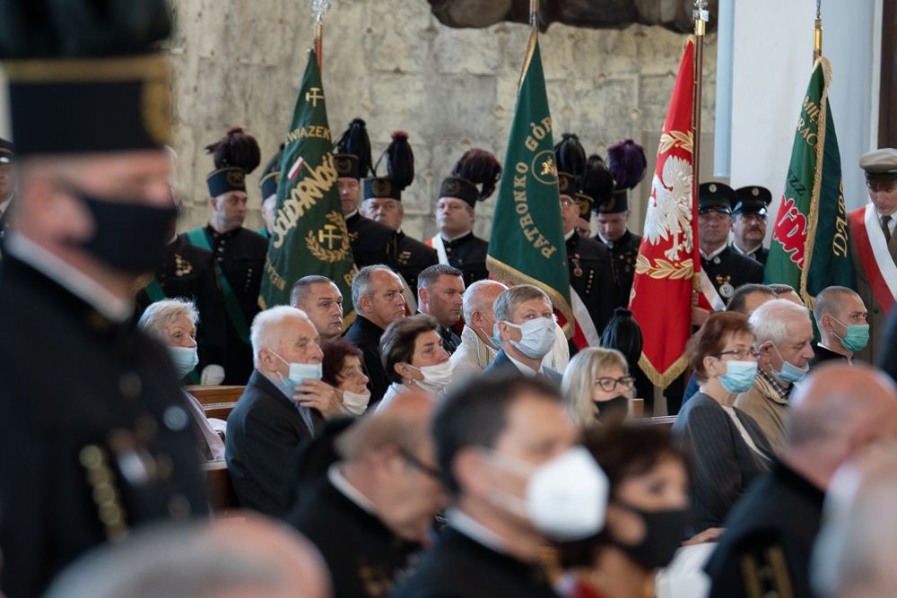 Zdjęcie przedstawia wiernych podczas mszy św. W tle poczty sztandarowe.