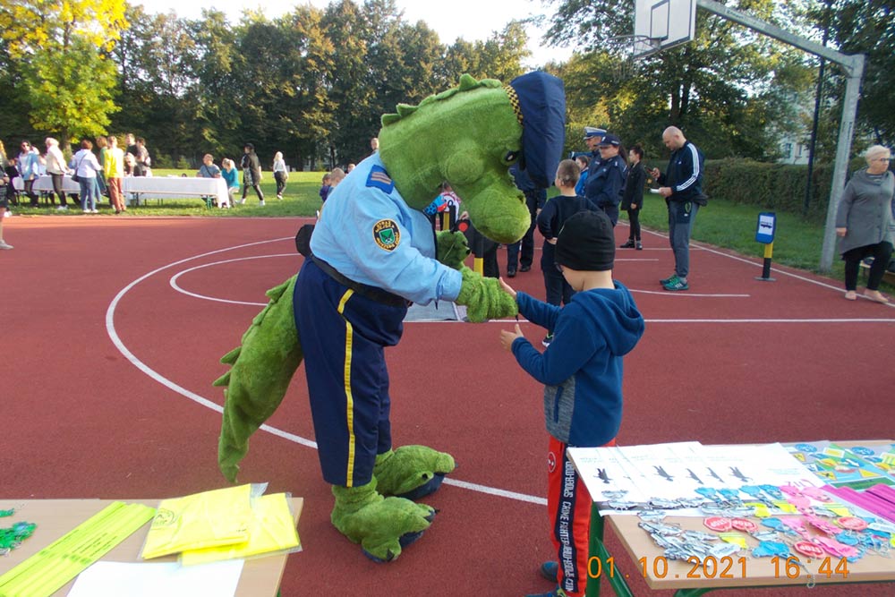 Strażnik przebrany za Smokusia - maskotkę straży rozmawia z dzieckiem.