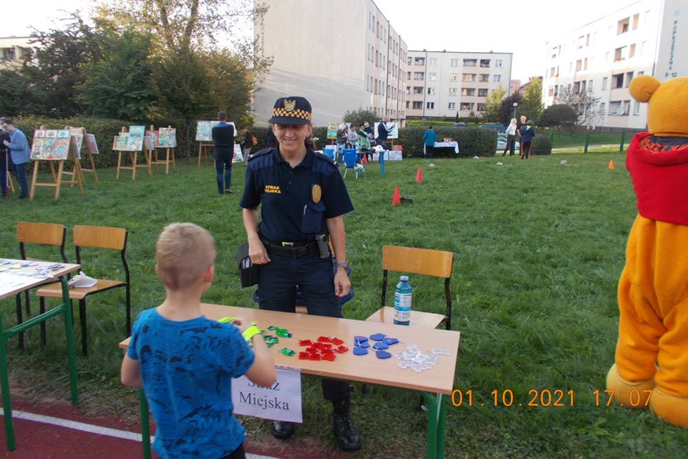 Stoisko Straży Miejskiej, przy nim strażniczka i dziecko.