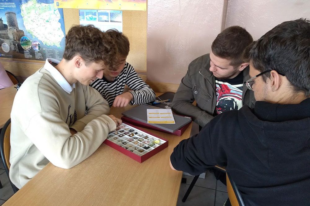 Uczniowie korzystający z pomocy dydaktycznych w jakiegoś rodzaju walizce-pojemniku.