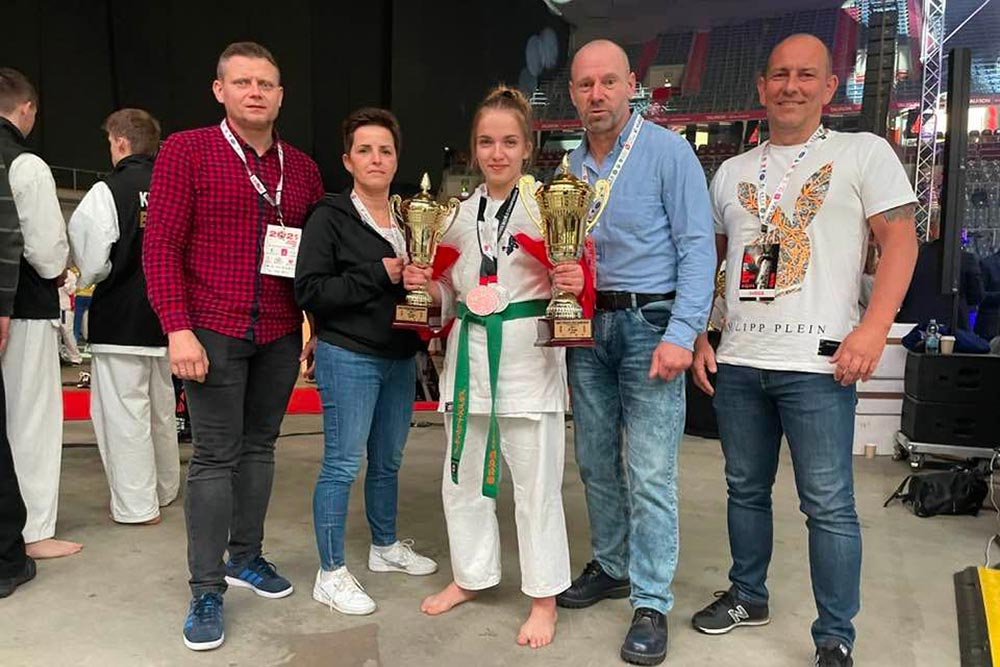 Marta Nalewajek pozuje do zdjęcia z dwoma pucharami. Wokół m.in. Shihan Janusz Piórkowski.