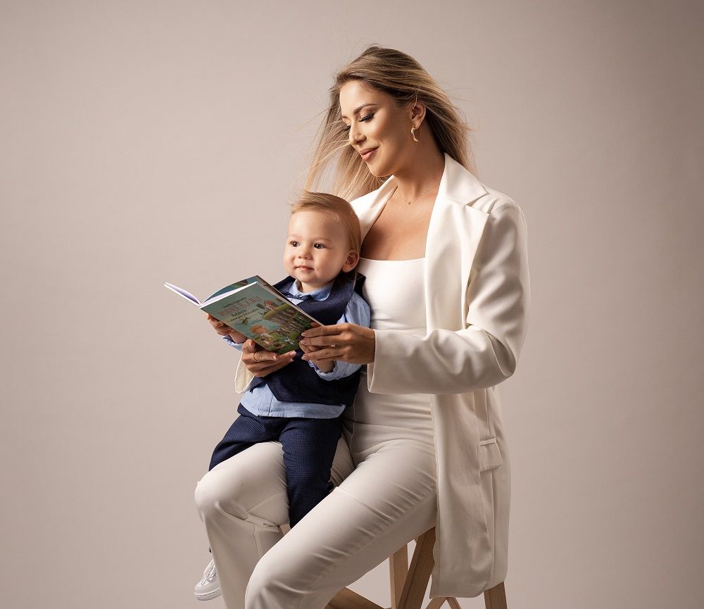 kobieta trzyma na kolanach syna i książkę